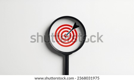 Magnifying glass enlarges the target arrow dart and dartboard on an isolated white background. Business goal strategy concept.