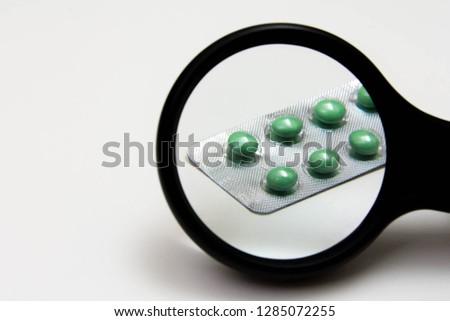Magnifying glass extended inspection medicine or fake. Checks verification medicinal on white for copy space.
Medicines and pills quality control concept.
