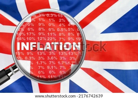Magnifying glass focused on the word inflation on UK flag background. Hike interest rate. Inflation income crisis. Inflation, tax, cash flow and another financial concept in Britannia