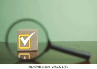 Magnifying Glass Focuses on Wooden Cube with Check Mark Icon, Symbolizing Achievement and Opportunity. - Powered by Shutterstock