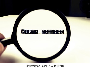 Magnifying glass focussed on the word 'Yield Farming' on the building blocks, search for the meaning on Cryptocurrencies and e-commerce.