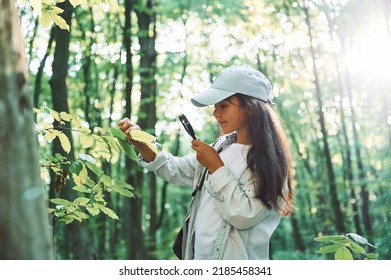 With magnifying glass. Girl is in the forest at summer day time discovering new places. - Shutterstock ID 2185458341