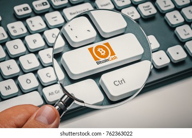 Magnifying Glass In Hand Focused On Computer Key With Bitcoin Cash Logo