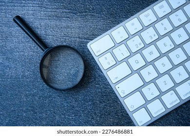 the magnifying glass and keyboard are the perfect combination as a concept in the search of right keywords that will improve your website's search engine ranking.