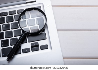 Magnifying glass laying on a laptop keyboard. Technology file search tool concept, data forensics, computer crime and device investigation, closeup - Shutterstock ID 2019320423
