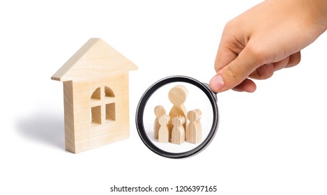 Magnifying Glass Is Looking At The Young Family With Children Is Standing Near A Wooden House. Loans For The Purchase Of Affordable Housing. Concept Of A Strong Family, The Continuation Of The Family.