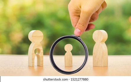 A Magnifying Glass Looks At A Child's Figure Stands Between Father And Mother. The Child Chooses Which Parent To Live With After Their Divorce. Guardianship Over Child. Interest Of Child