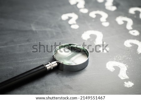 Magnifying glass and many question marks on the blackboard, FAQs, question analysis, education concept