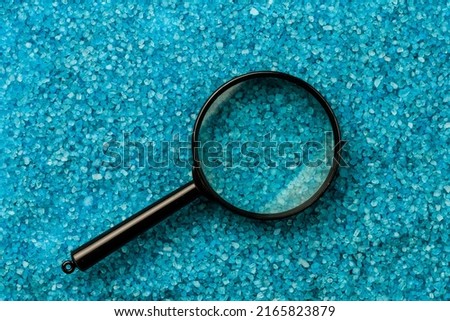 Magnifying glass on the background of sea aromatic bath salts. Concept of searching for romantic pleasure. Abstract copy space