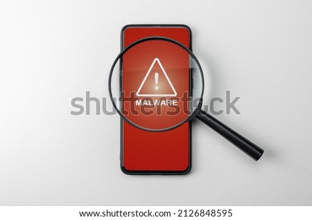Magnifying glass on cell phone, an alarm sign detecting malware. Virus malware under magnifying glass, anti-virus finds malicious app. Search for malware