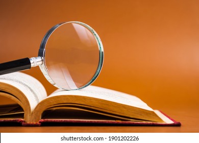 Magnifying glass on opened old book for searching and reading concept