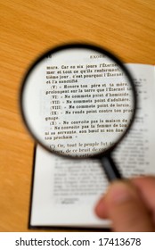 Magnifying Glass On A Page Of The Bible In French (Exodus).  Focus On The Ten Commandments.