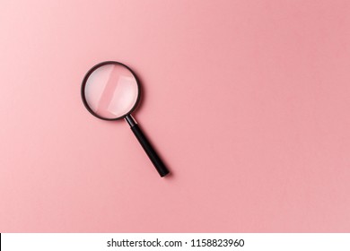 Magnifying glass on pink background. Top view. Flat lay. Copy space. Concept