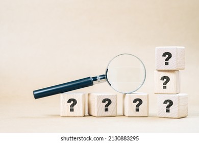 Magnifying glass on wood cubes with many question marks, confusing, frequently asked questions, and doing test concept - Shutterstock ID 2130883295