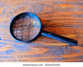 A magnifying glass on a wooden table - Powered by Shutterstock