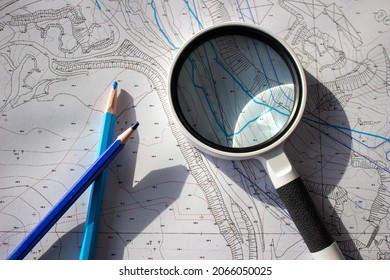 A magnifying glass and pencils on a planning basemap. - Shutterstock ID 2066050025