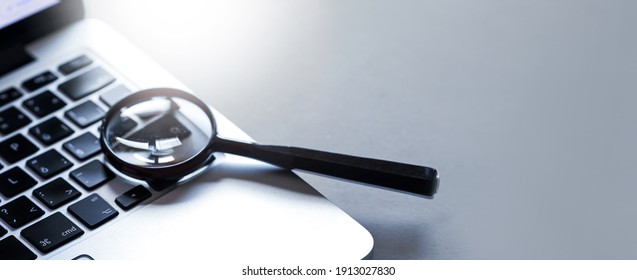 Magnifying glass put on close up of Laptop computer. Internet search concept. Wide banner or panorama. 