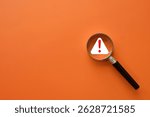 Magnifying Glass with a Red Warning Triangle Over an Orange Background, Representing Caution and Alert in Business or Safety Contexts.