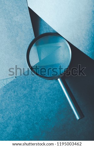 magnifying glass. science research exploration and scrutiny concept. loupe on layered blue paper background.