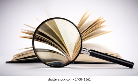 Magnifying glass set in front of antique book with fanned pages