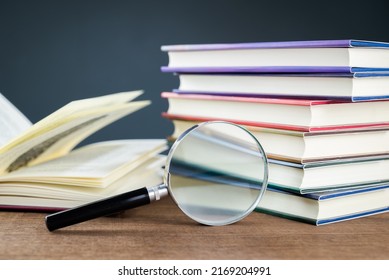Magnifying glass and stack of hardcover books, research, searching information concept