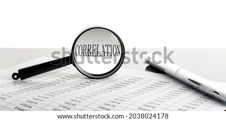Magnifying glass with text CORRELATION on background with pen