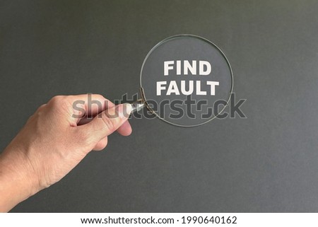 Magnifying glass with text Find Fault. Dark grey background.