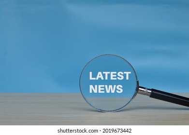 Magnifying glass with text LATEST NEWS isolated on blue background - Shutterstock ID 2019673442