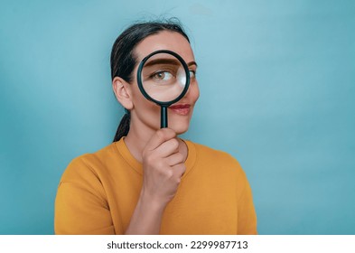Magnifying glass. Woman's face through magnifying glass. Big eyes. Research, choice concept.