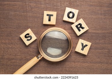 Magnifying glass with wood blocks of STORY word on woof background, finding a story idea - Shutterstock ID 2224391623
