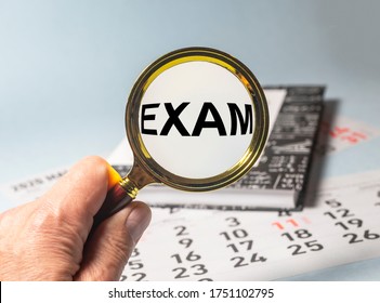 Magnifying glass with the word exam on book of maths or physics on calendar sheets on blue table. Searching exam concept. preparing for exam concept - Shutterstock ID 1751102795