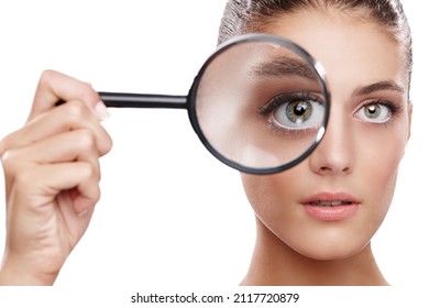 Magnifying Her Best Features. Studio Shot Of A Beautiful Woman With A Magnifying Glass In Front Of Her Eye.