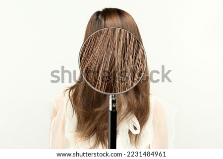 Magnifying a woman's hair with a loupe.