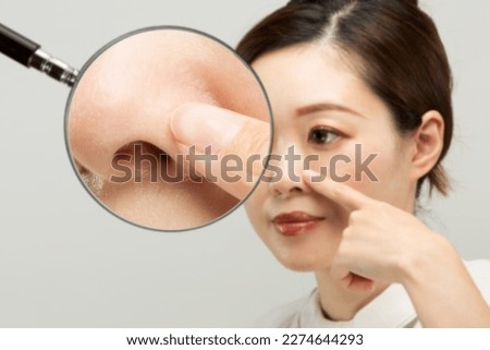 Magnifying a woman's nose with a loupe.