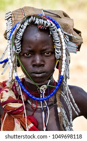 Mago National Park, Omo River Valley, Ethiopia - December 22, 2010: Portrait of a Mursi woman. The women of the Mursi tribe have a lip plate and iron decorations - Shutterstock ID 1049698118