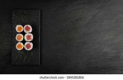 Maguro Tuna Hosomaki Sushi Mockup On Dark Background Top View With Copy Space. Small Maki Sushi Rolls With Raw Trout, Salmon And Nori