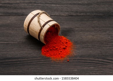 Magyar (Hungarian) brilliant red sweet paprika powder. Traditional seasoning for cooking national food. Wooden keg, black wooden background, copy space