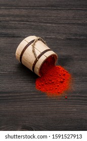Magyar (Hungarian) brilliant red sweet paprika powder. Traditional seasoning for cooking national food. Wooden keg, black wooden background, copy space, close up