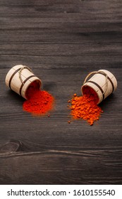 Magyar (Hungarian) brilliant red sweet and hot paprika powder. Traditional seasoning for cooking national food. Wooden kegs, black wooden background, copy space