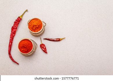 Magyar (Hungarian) red sweet and hot paprika powder. Traditional seasoning for cooking national food, different varieties of dry pepper. Wooden kegs, stone concrete background, copy space, top view