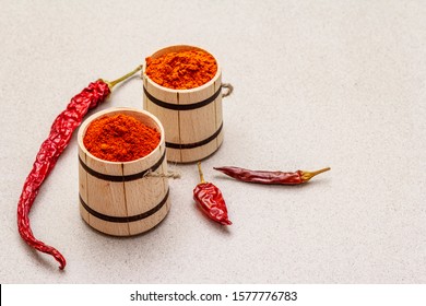 Magyar (Hungarian) red sweet and hot paprika powder. Traditional seasoning for cooking national food, different varieties of dry pepper. Wooden kegs, stone concrete background, copy space