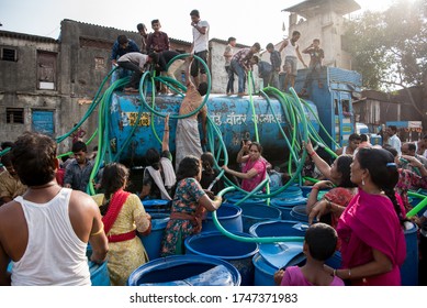 MAHARASHTRA/INDIA - MAY 15, 2016 : Residents climb a municipal water tanker to filling water in their containers in Bhiwandi