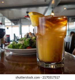 Mai Tai Cocktail With Orange Segment, In Short Glass On A Bar Counter, Shallow Focus, Salad In Background