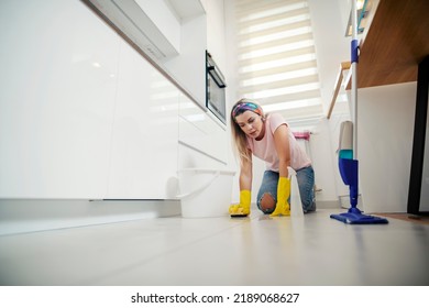 A Maid Cleaning Dirty Kitchen Floor In Apartment With Detergent And Sponge.