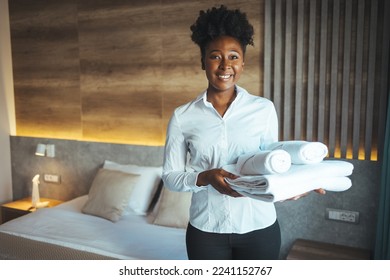 Maid with fresh clean towels during housekeeping in a hotel room. Maid making bed in hotel room. Maid with fresh towels in hotel room. Maid cleaning bedroom after guests, focus of clean towels - Shutterstock ID 2241152767