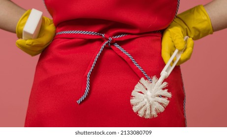 Maid Holding Toilet Brush And Cleaning Sponge Behind Her Back