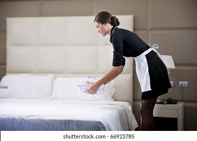 Maid Making Bed In Hotel Room