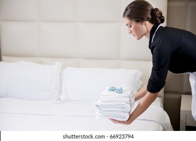 Maid making bed in hotel room