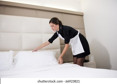 Maid Making Bed In Hotel Room