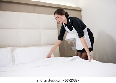 Maid Making Bed In Hotel Room